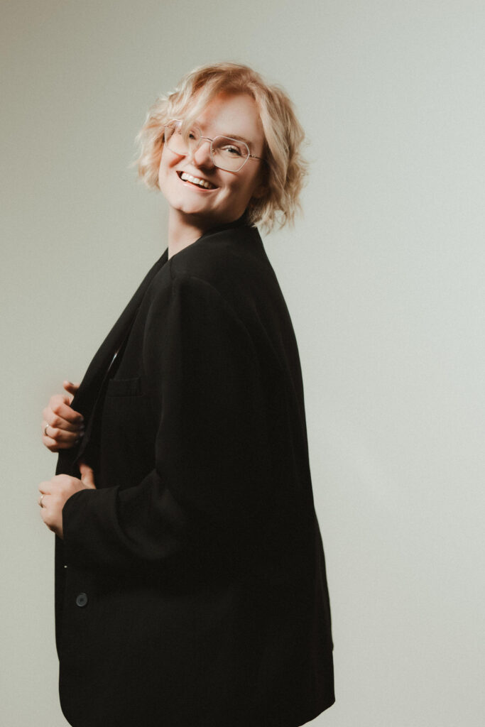 Fotografin Laura Viermann mit blondem, lockigem Haar und schwarzem Blazer lächelt in die Kamera.